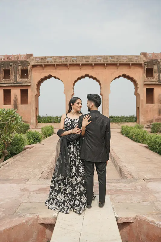 Grand couple portrait at Jaigarh Fort sandstone ramparts overlooking the valley